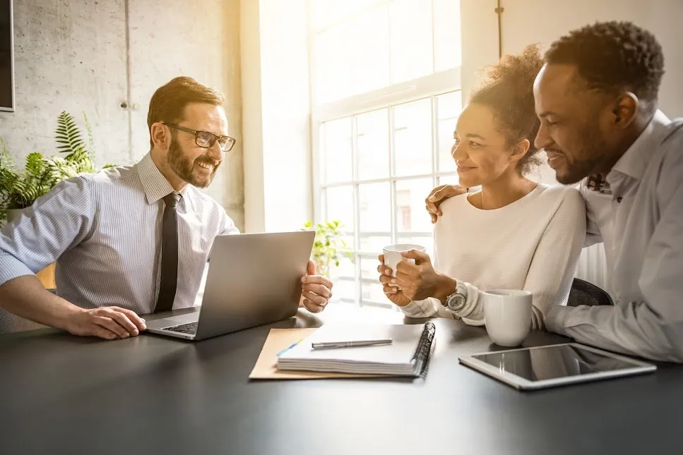 An advisor talking with a couple across an office desk.