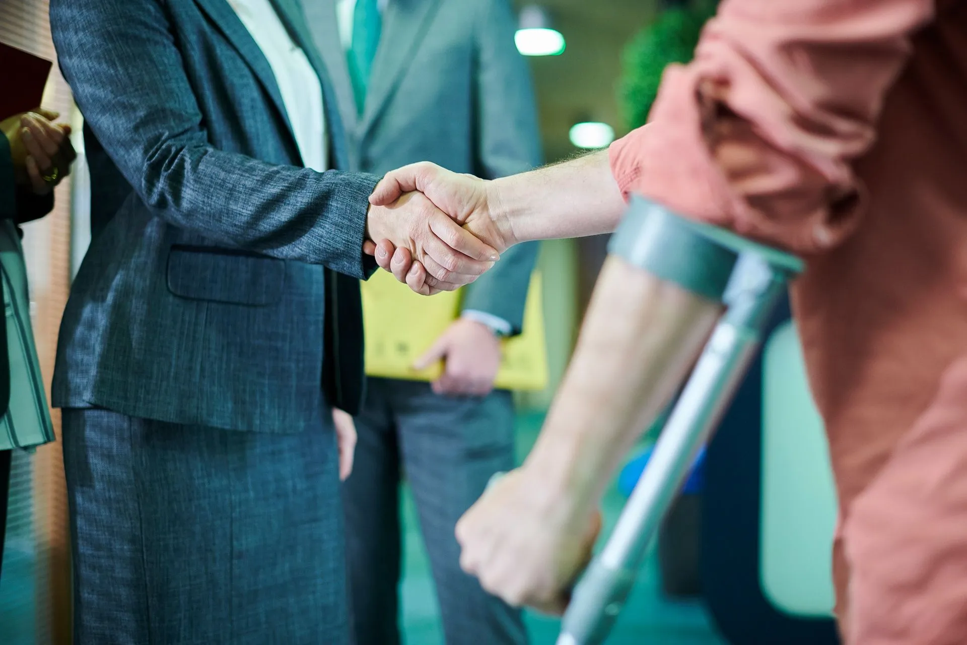A businesswoman shaking hands with a person on crutches.