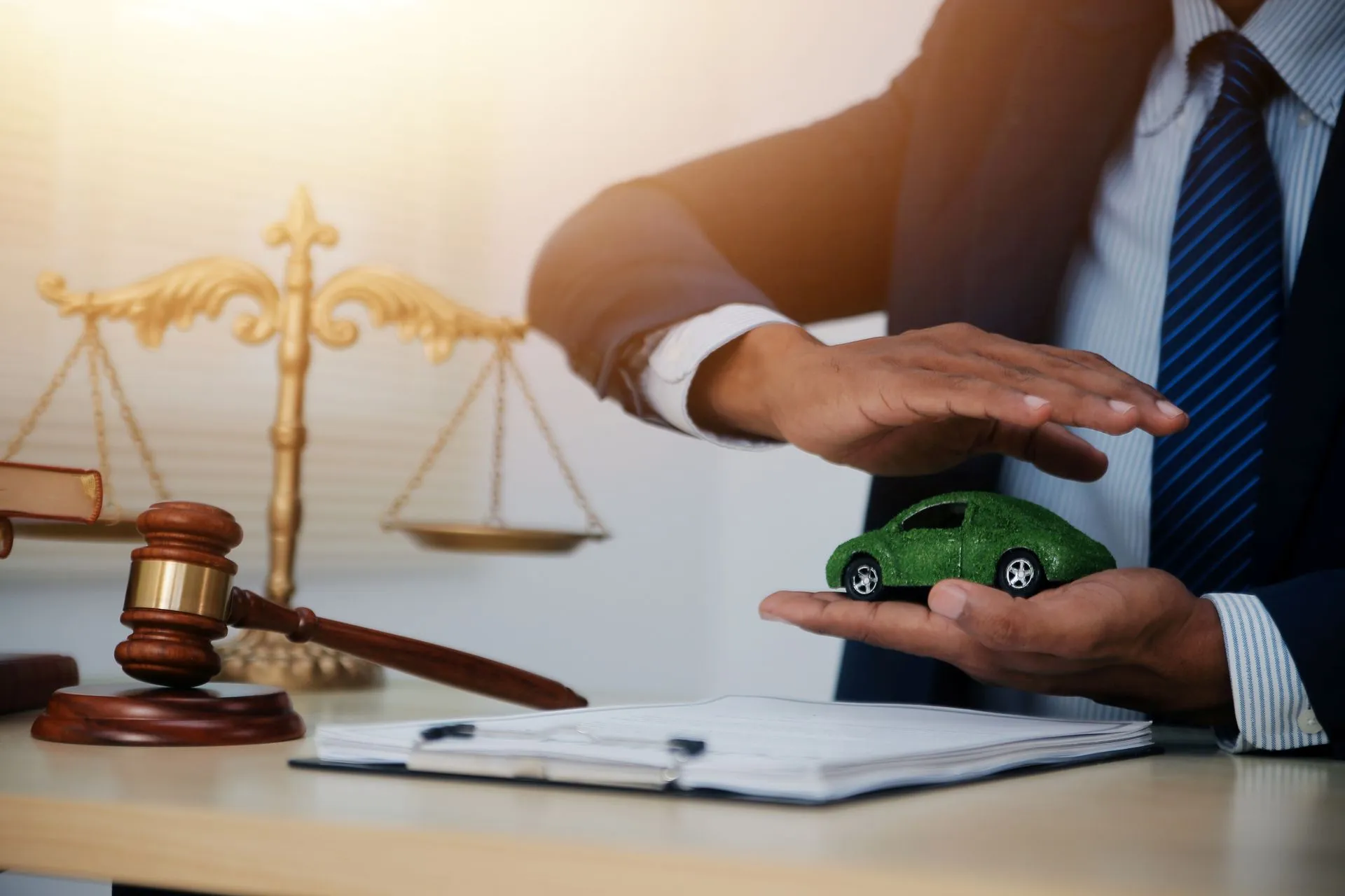 A person in a suit protecting a miniature green car model.