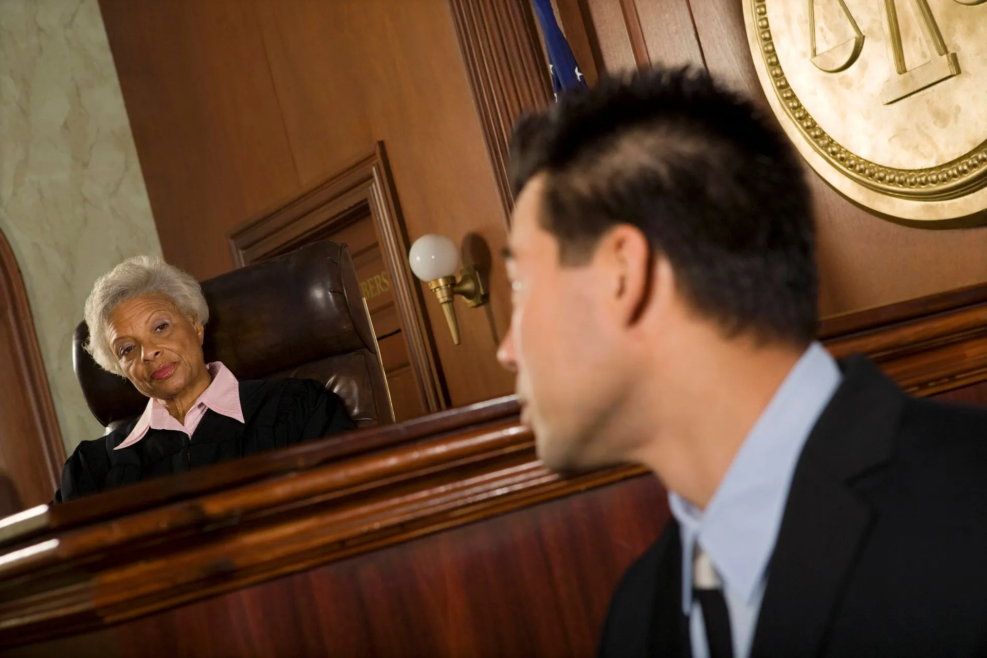 A female judge looking at a man in a courtroom setting.