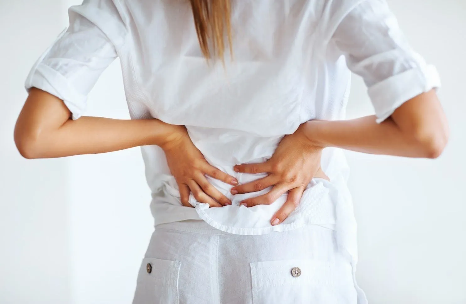 A woman holding her lower back in pain.
