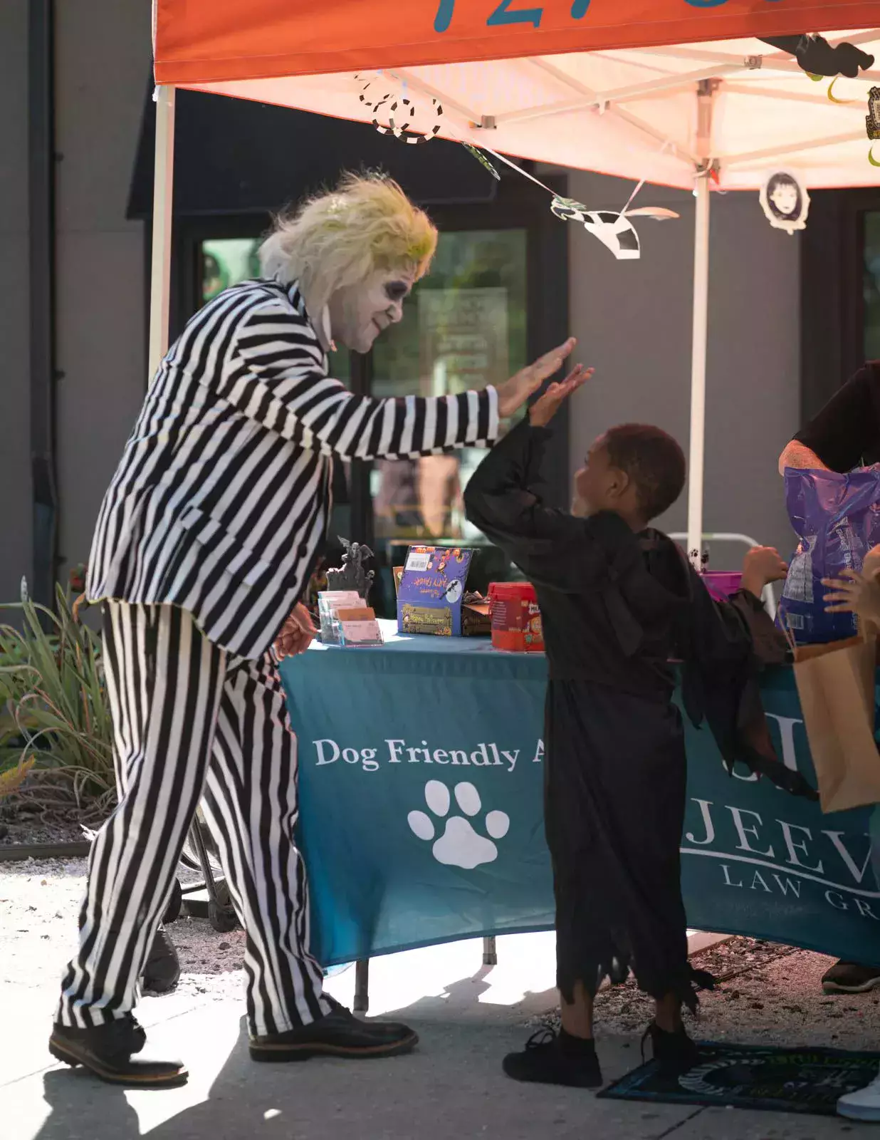 A man in a striped suit is giving a child a high five