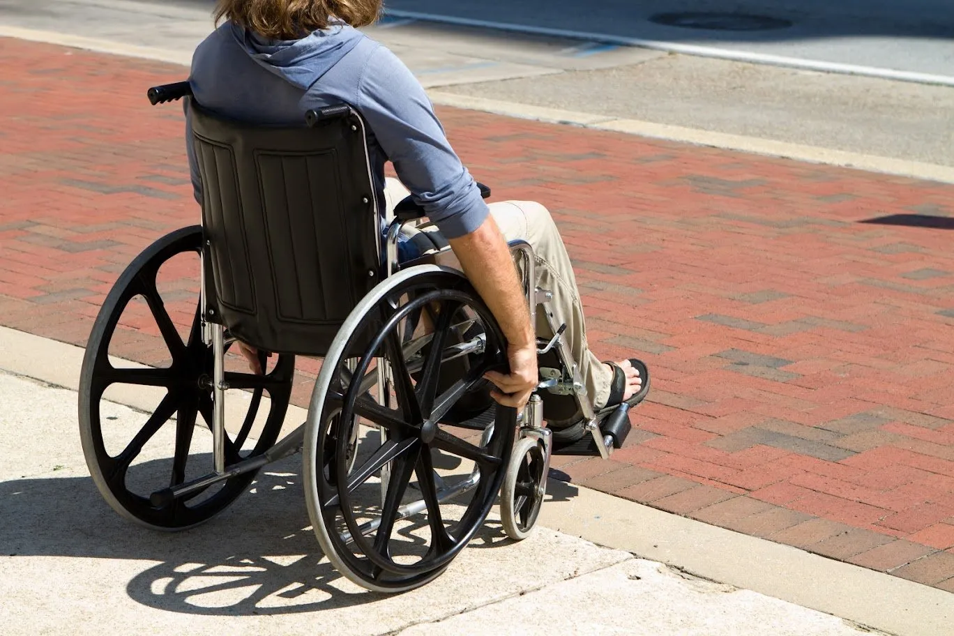 A person sitting in a wheelchair on a brick path.
