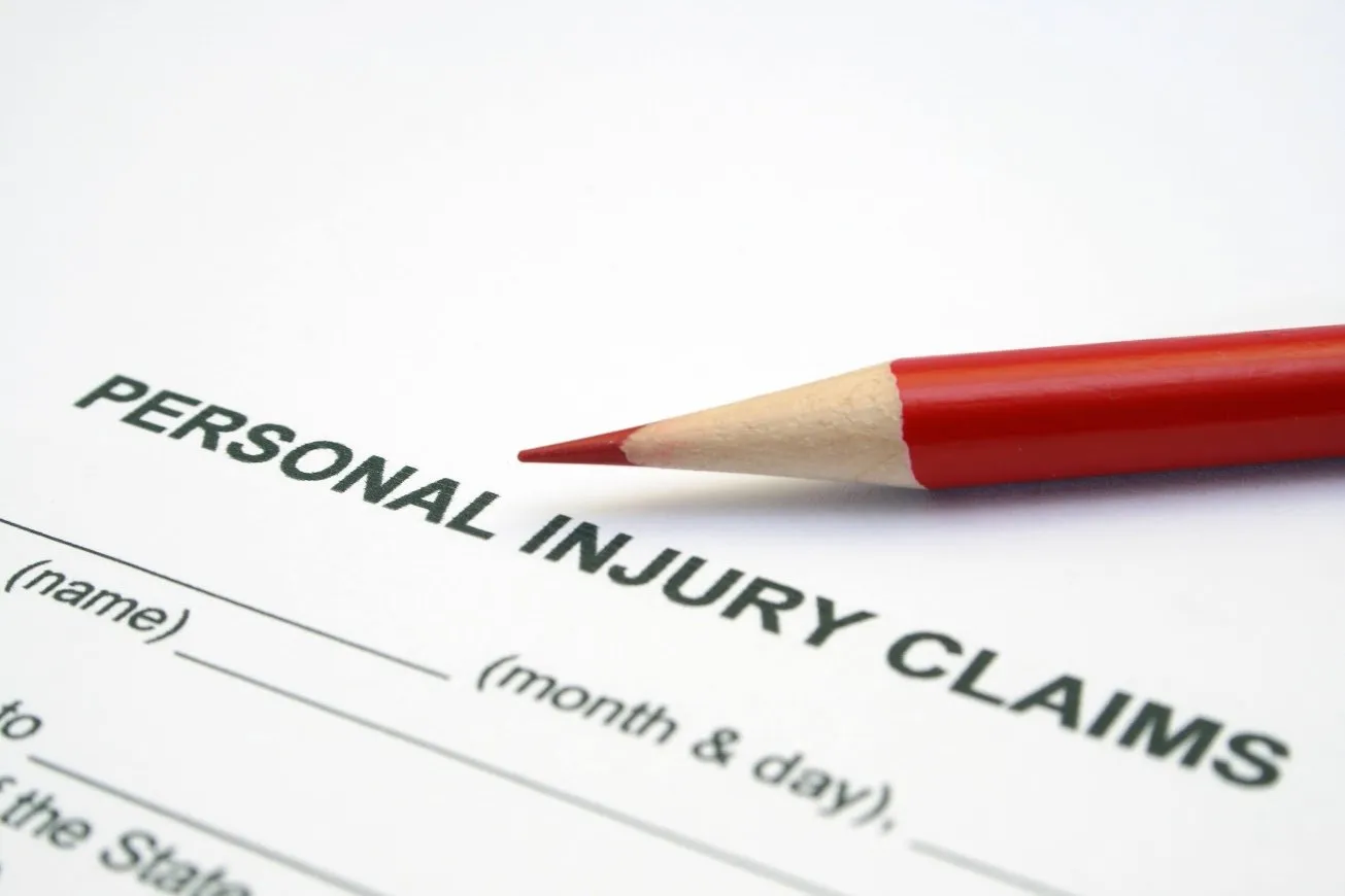 A red pencil resting on a 'Personal Injury Claims' form.