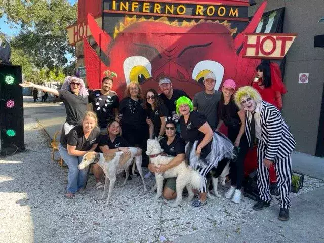 A group of people posing in front of a sign that says inferno room hot