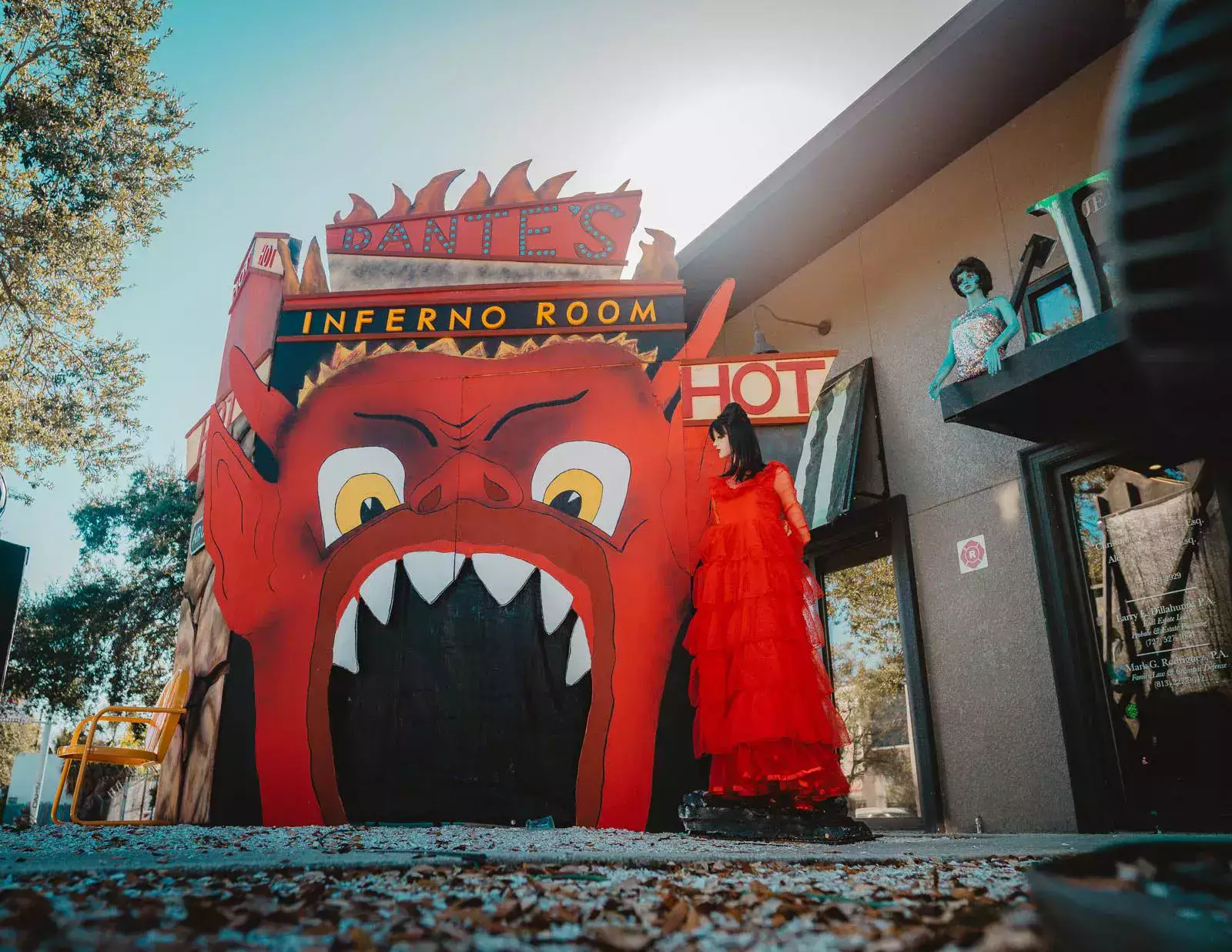 A woman in a red dress is standing in front of an inferno room.