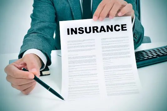 A person holding a pen and a 'Insurance' document.