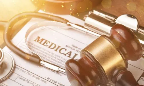 A gavel and a stethoscope resting on a 'Medical' document.