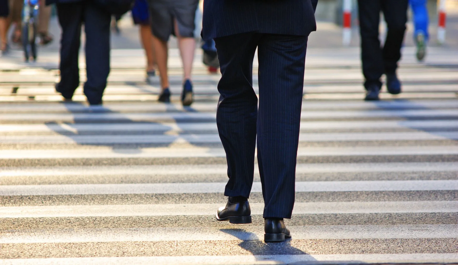 People walking across a pedestrian crosswalk in a city.