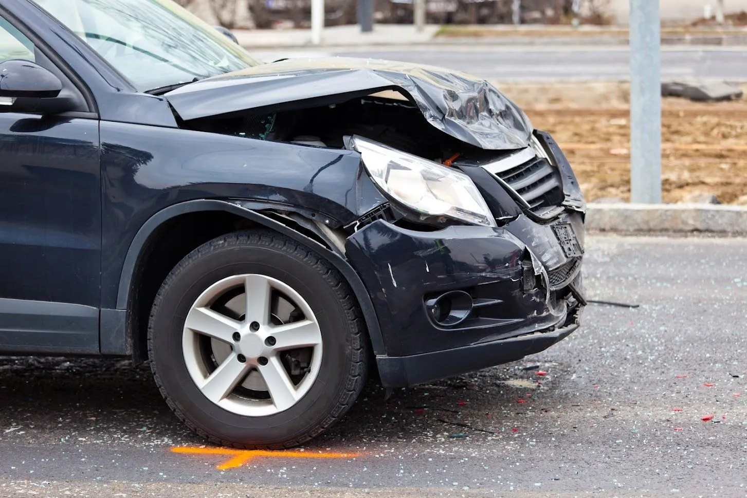 A dark SUV with front-end damage from a crash.