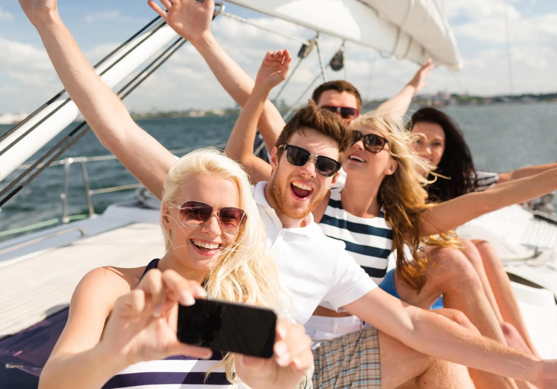 A group of happy friends taking a selfie on a boat.