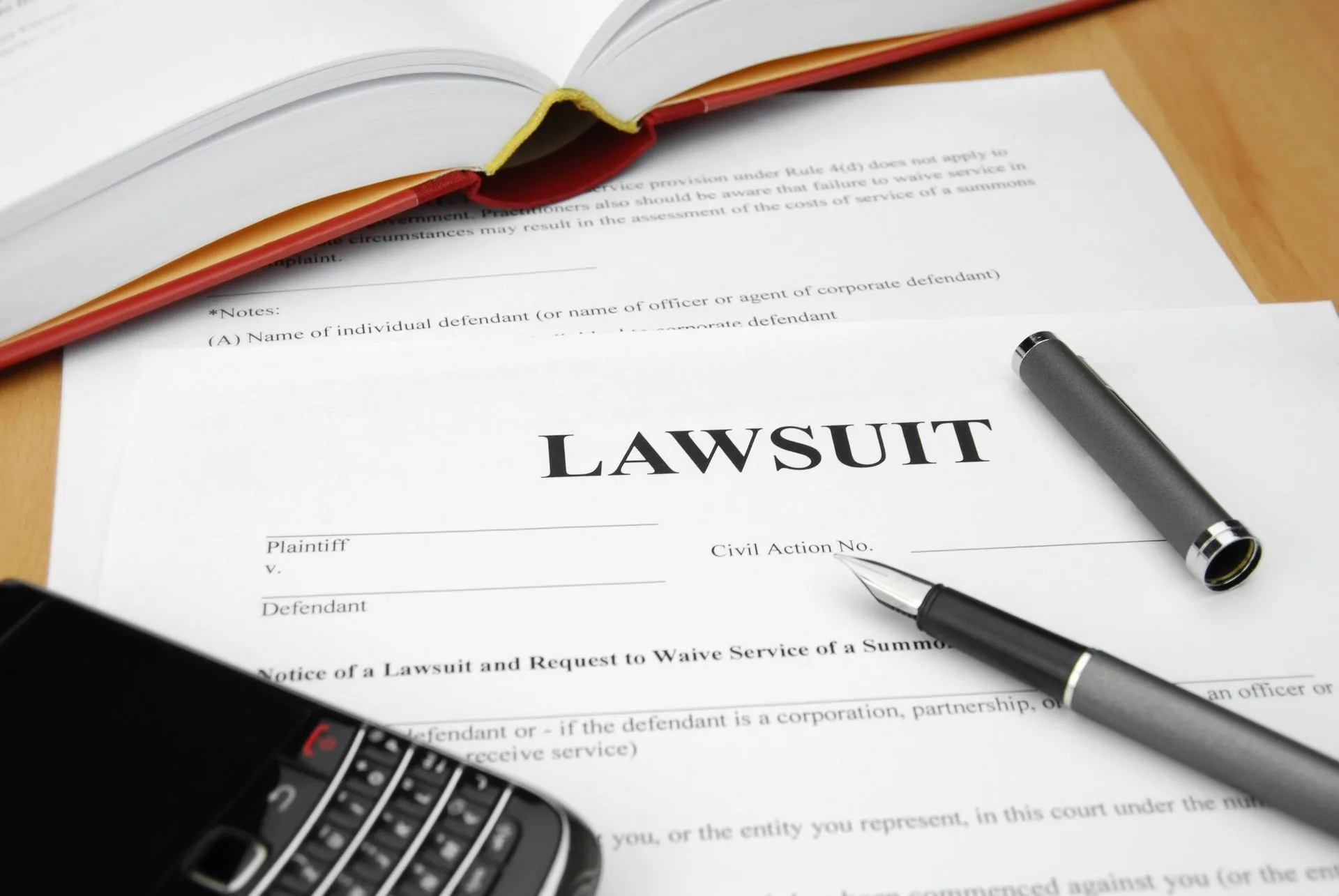 A document titled 'Lawsuit' with a pen, phone, and a legal book.