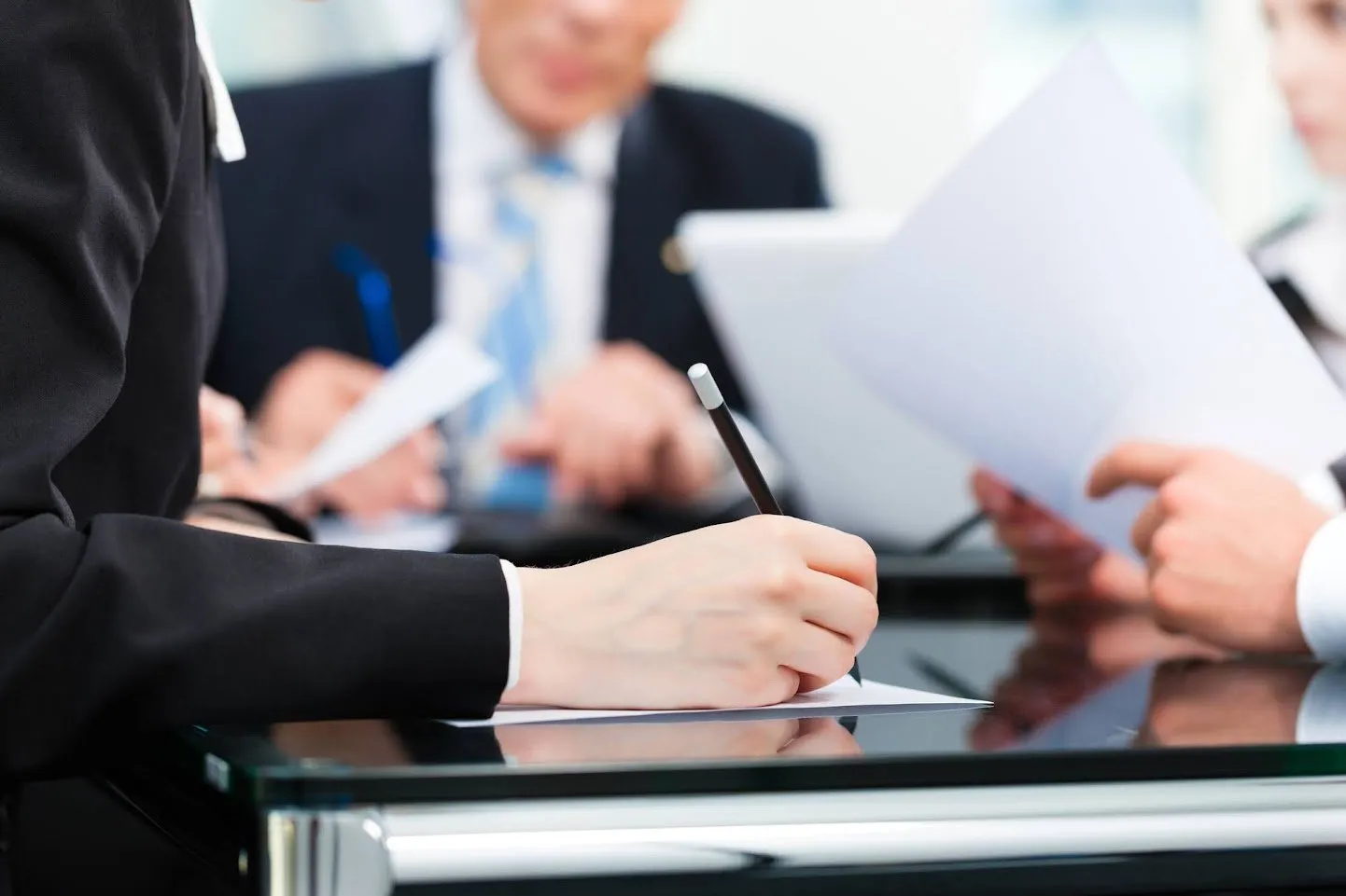 A person signing a document at a business meeting.