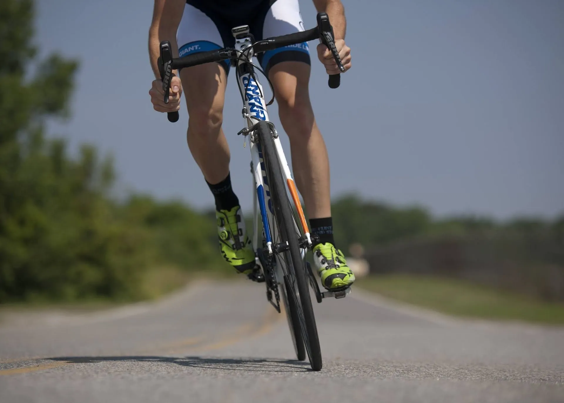 Cyclist riding a road bike forward on an empty country road.