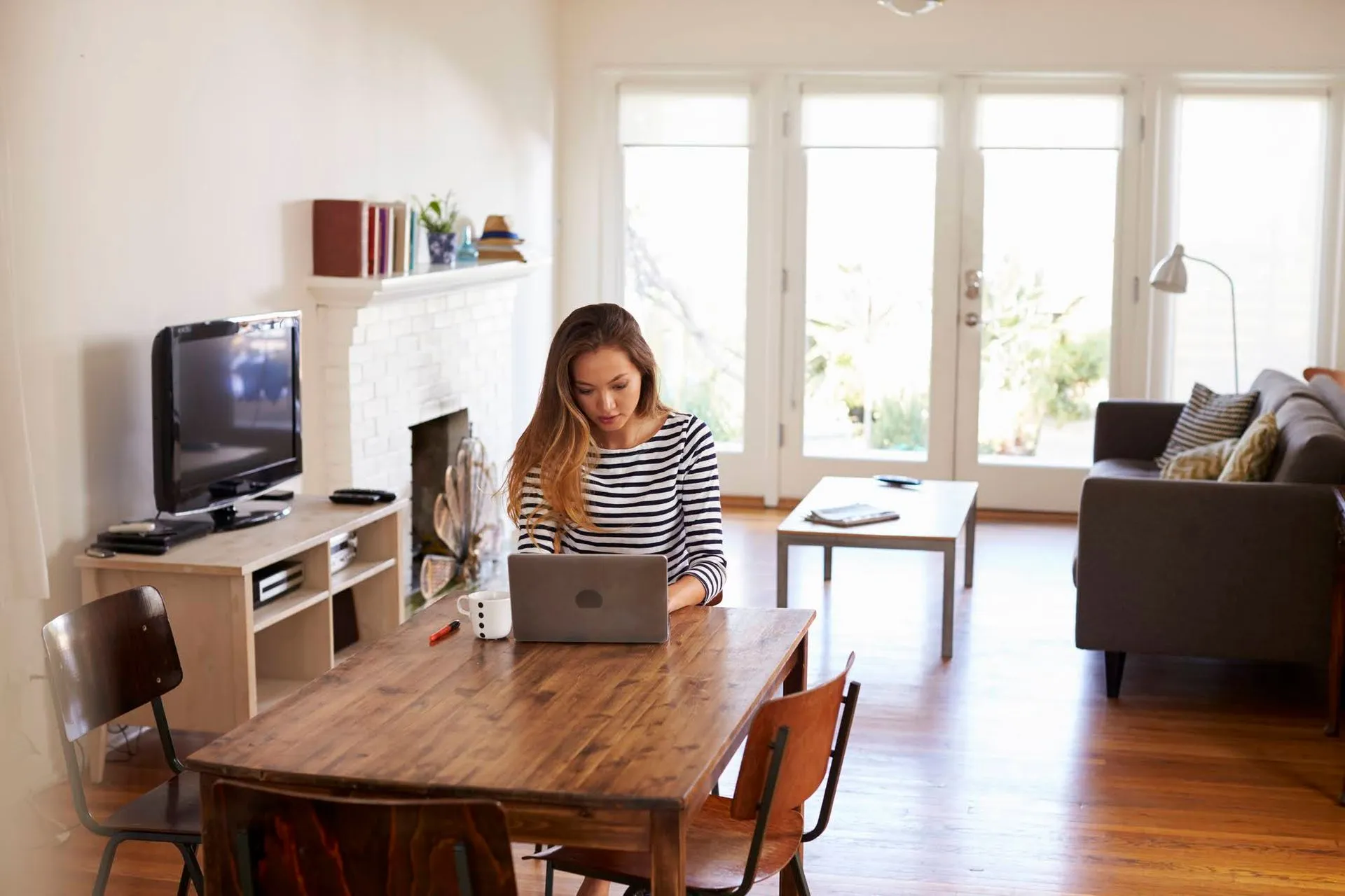 A woman working on a laptop at a table indoors.