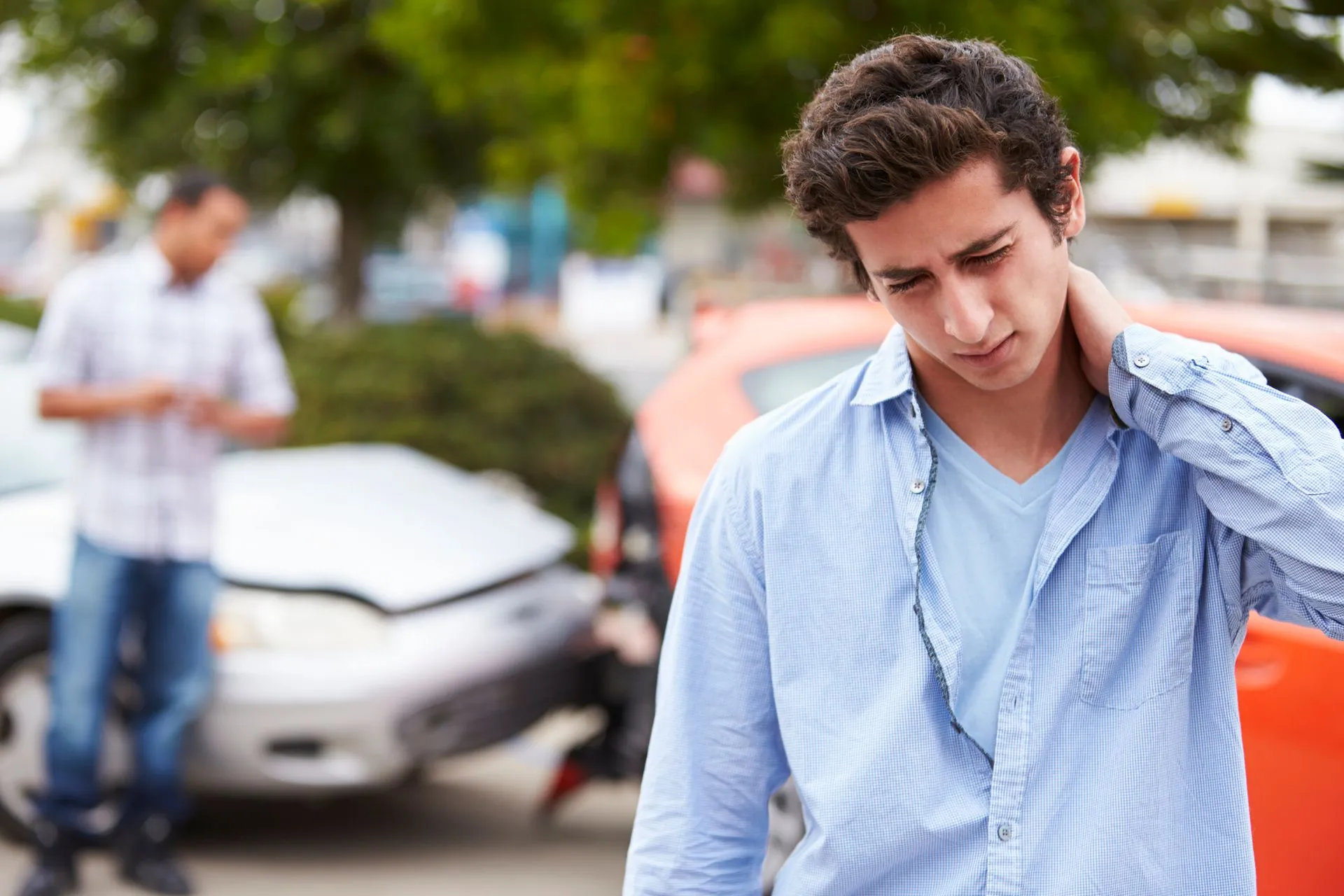 A young man holding his neck in pain after a car crash.