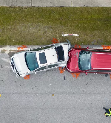 Aerial view of a white car rear-ending a red SUV on a street with orange collision markers around the vehicles.