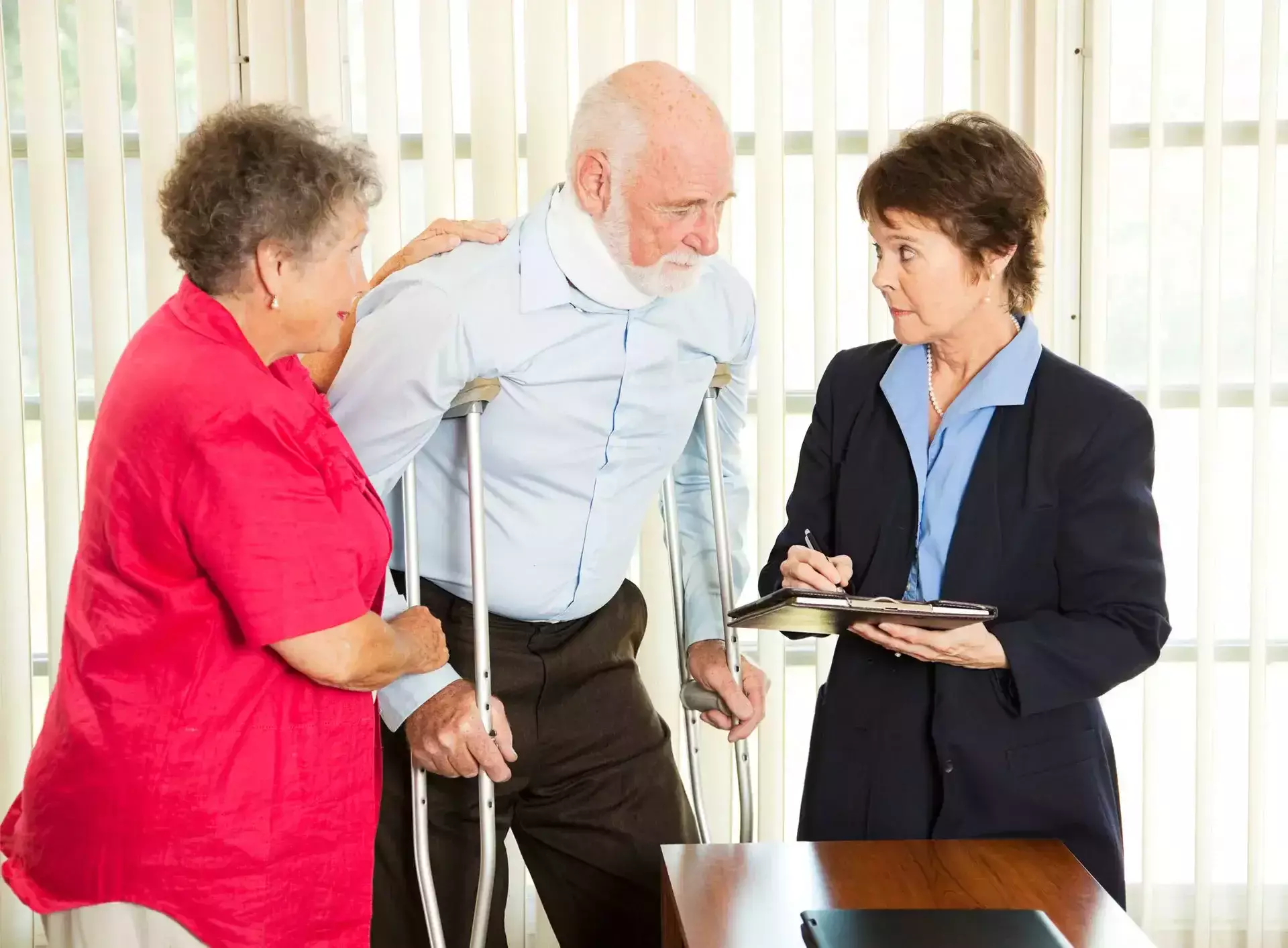 An injured elderly man on crutches talking with a professional.