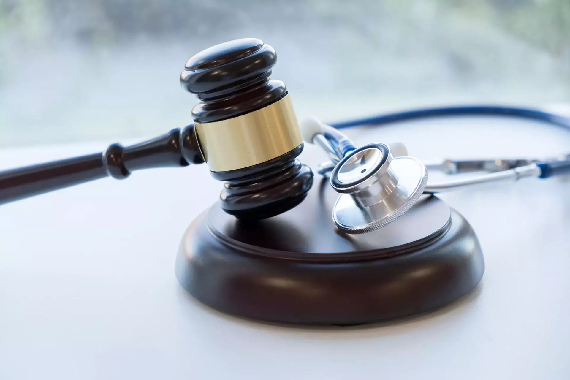 Wooden judge's gavel and a medical stethoscope on a white surface.