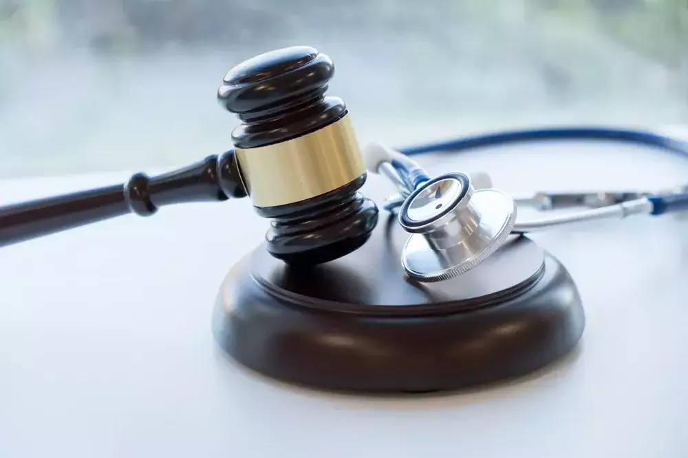 Wooden judge's gavel and a medical stethoscope on a white surface.