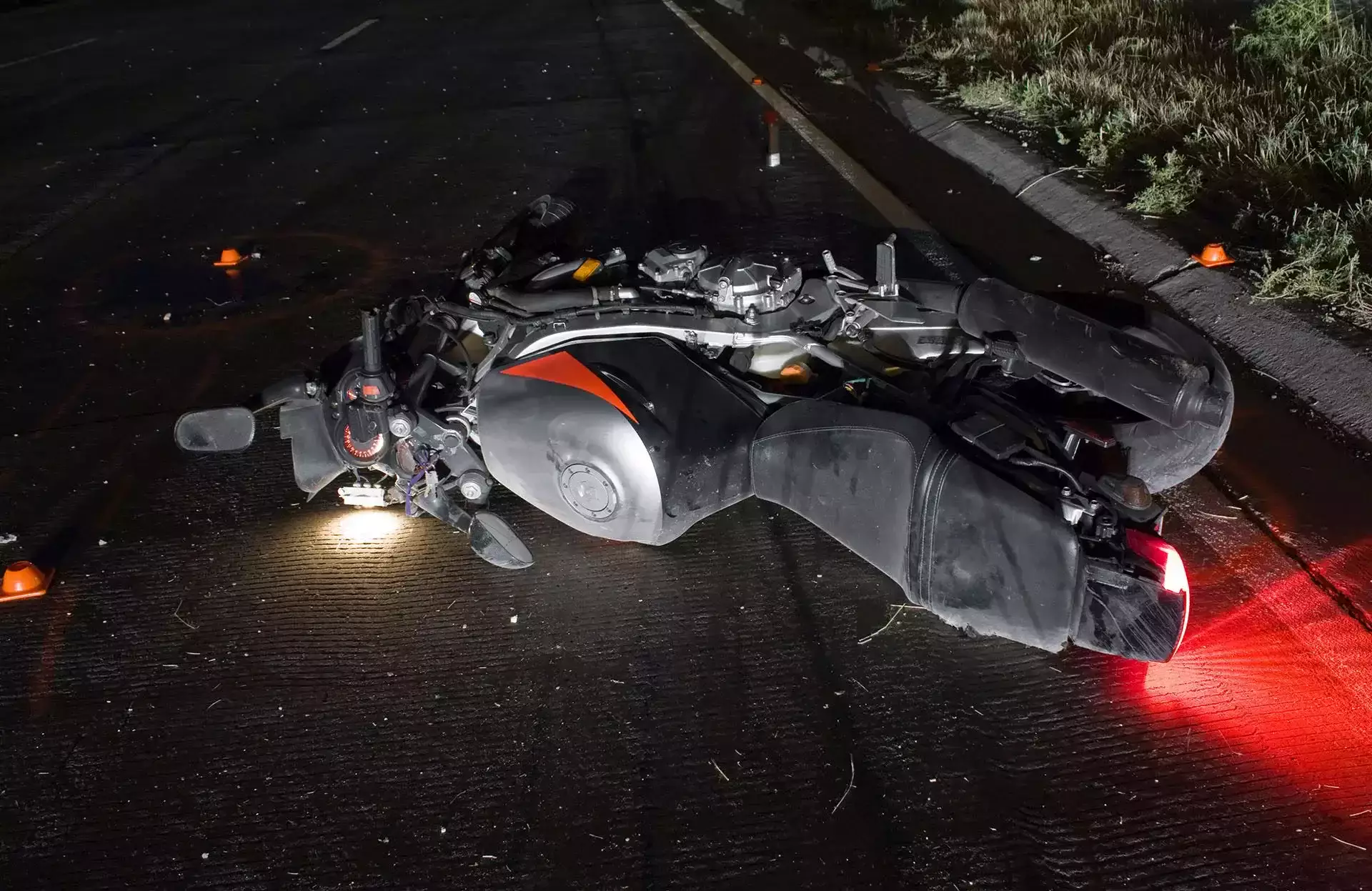 Damaged motorcycle lying on its side on a dark road at night.