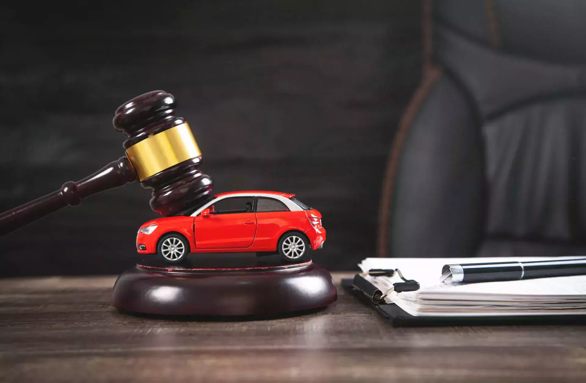 Un abogado especializado en accidentes automovilísticos está representado por un mazo junto a un coche de juguete rojo y documentos legales.