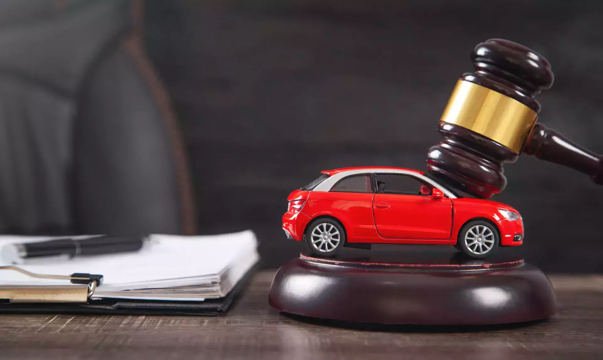 Un mazo golpeando junto a un coche de juguete rojo sobre un escritorio simboliza un caso de accidente automovilístico y una acción legal.