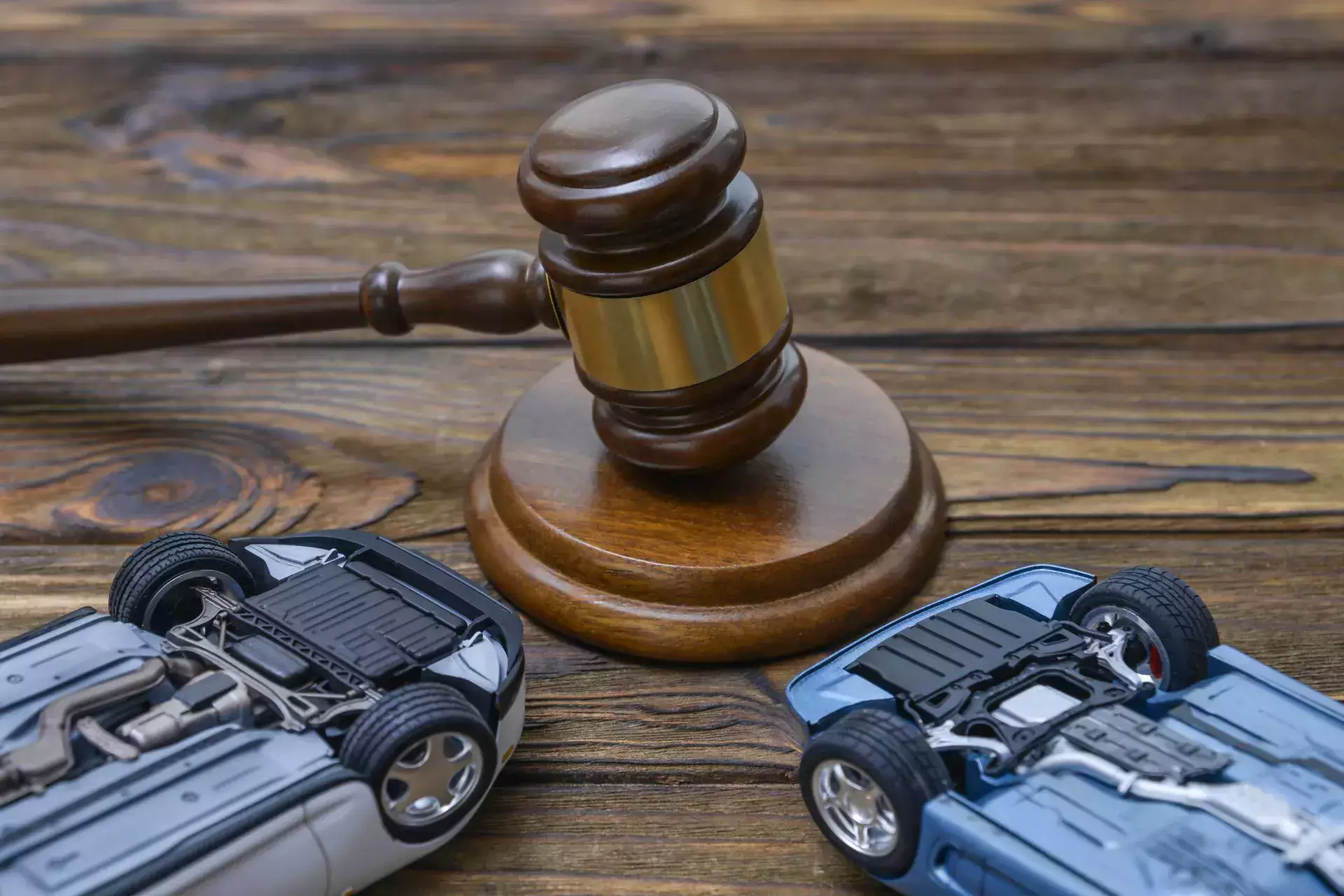 Ilustración sobre abogados de accidentes de tráfico que muestra un mazo de juez y una escena con miniaturas de automóviles dañados.