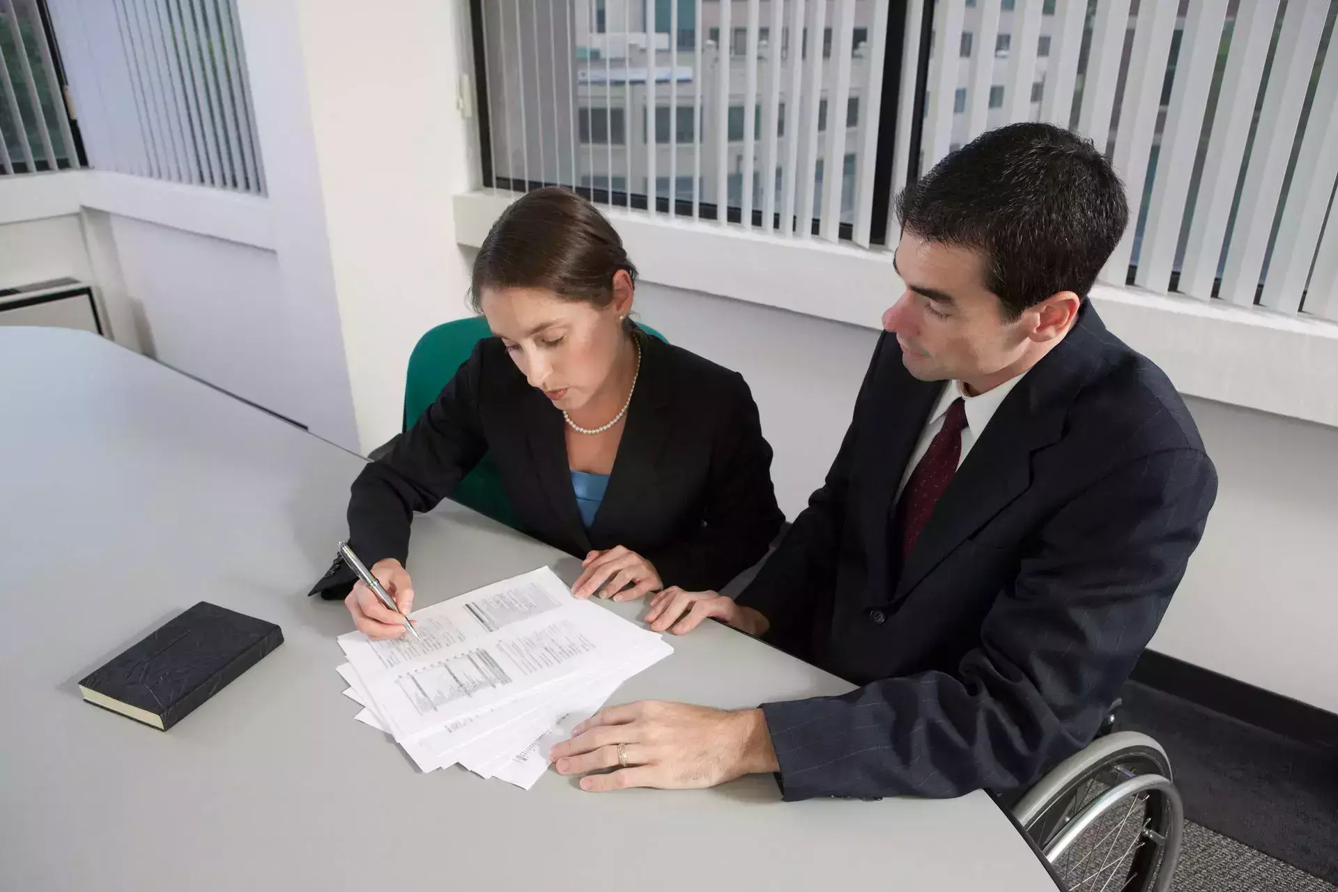 Un empresario con discapacidad firma un documento con la ayuda de un abogado especializado en lesiones personales.