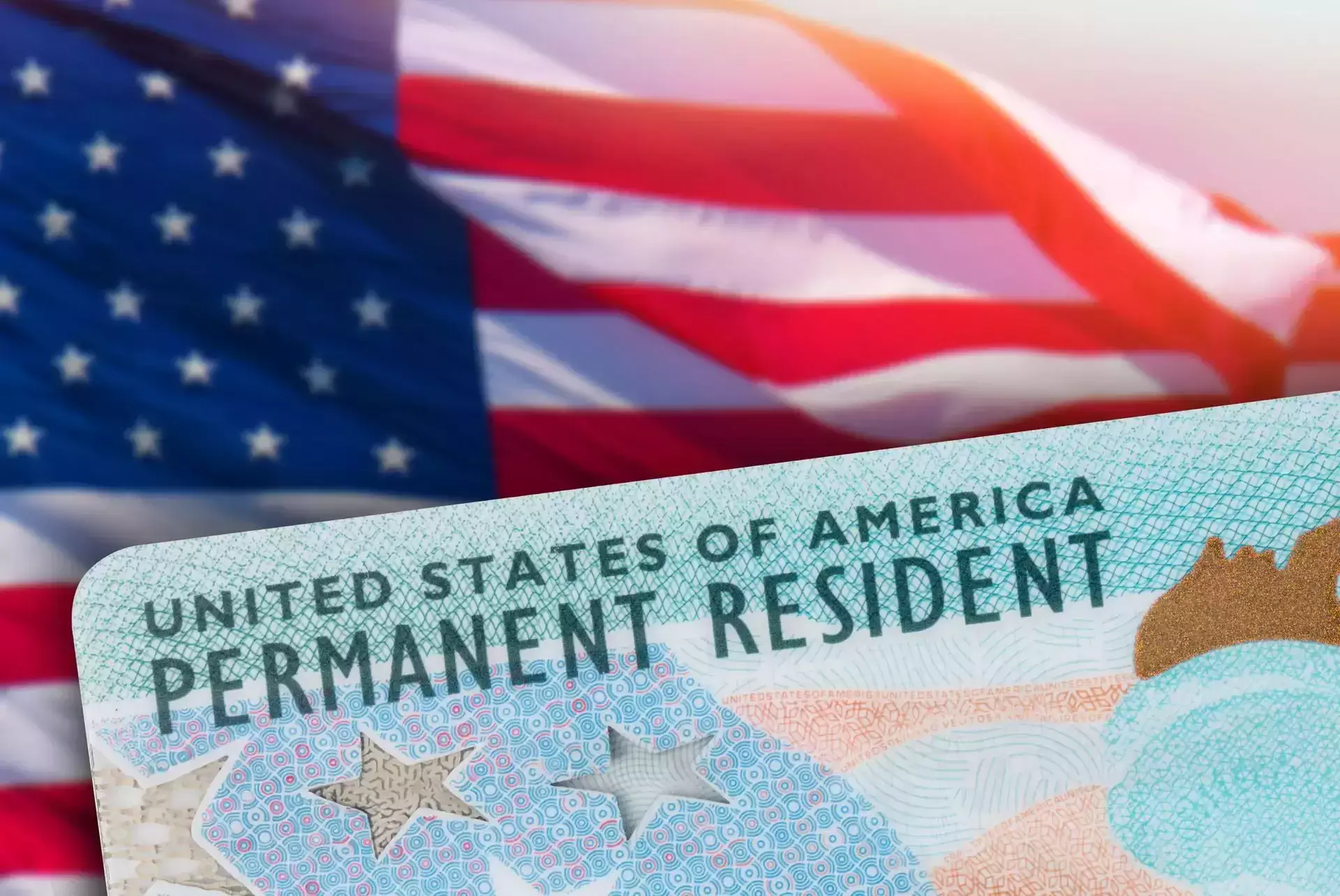 Tarjeta de residente permanente de los Estados Unidos mostrada frente a una bandera estadounidense.