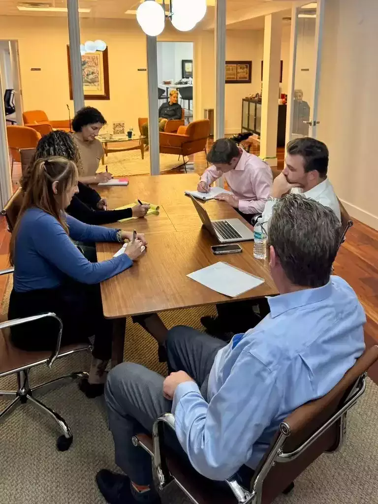 Equipo legal participando en una reunión colaborativa alrededor de una mesa de conferencias en un despacho de abogados.