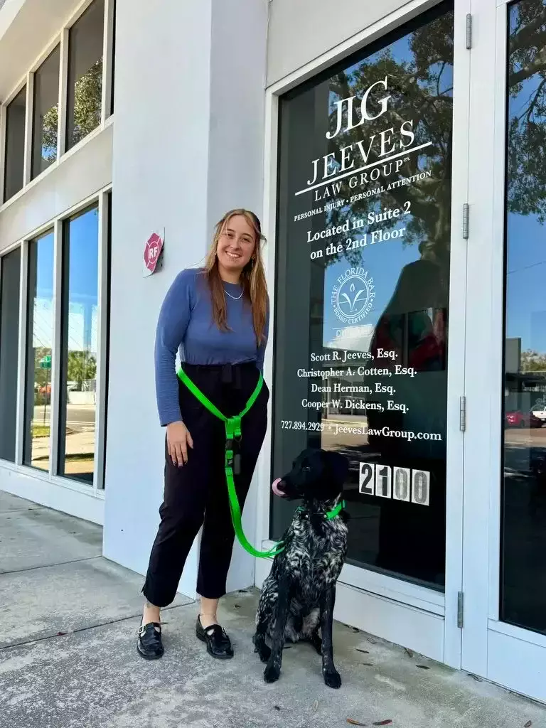Woman with a dog standing outside the Jeeves Law Group office entrance.