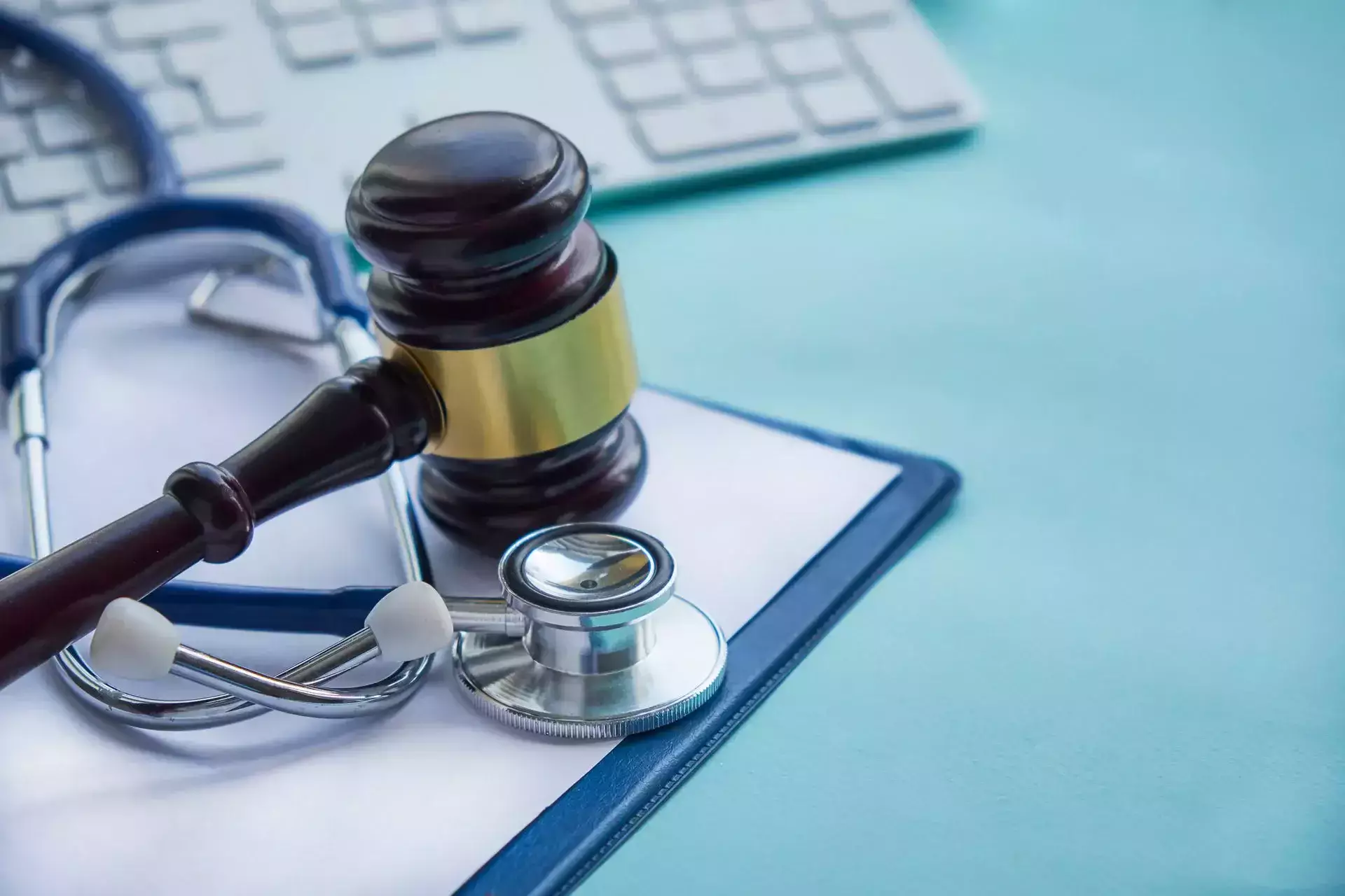 A judge's gavel and a stethoscope on a blue clipboard.
