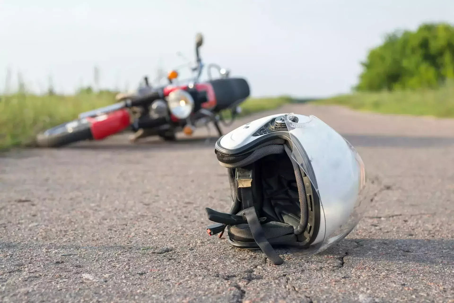A fallen motorcycle and helmet on a country road.