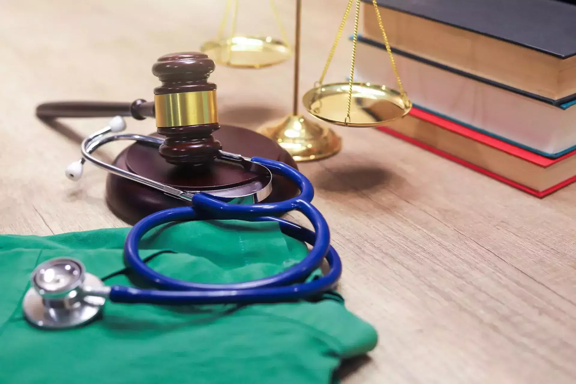 Un mazo de juez, un estetoscopio y un ambo médico en un escritorio de madera.