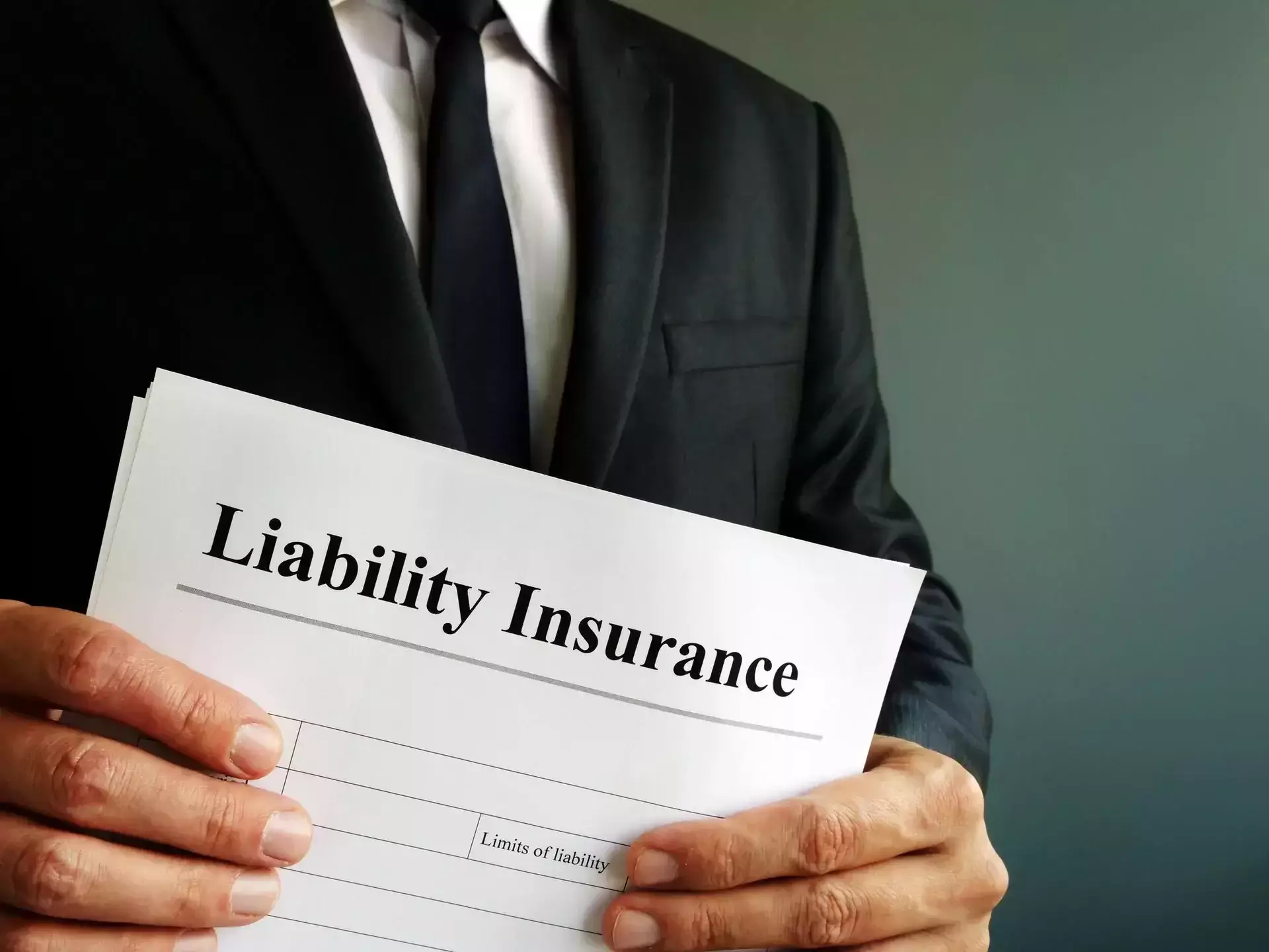 A person in a suit holding a document titled 'Liability Insurance'.