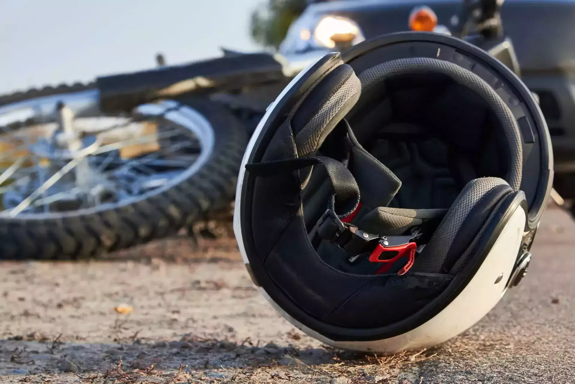 Un casco de motocicleta en la carretera con una moto caída detrás.