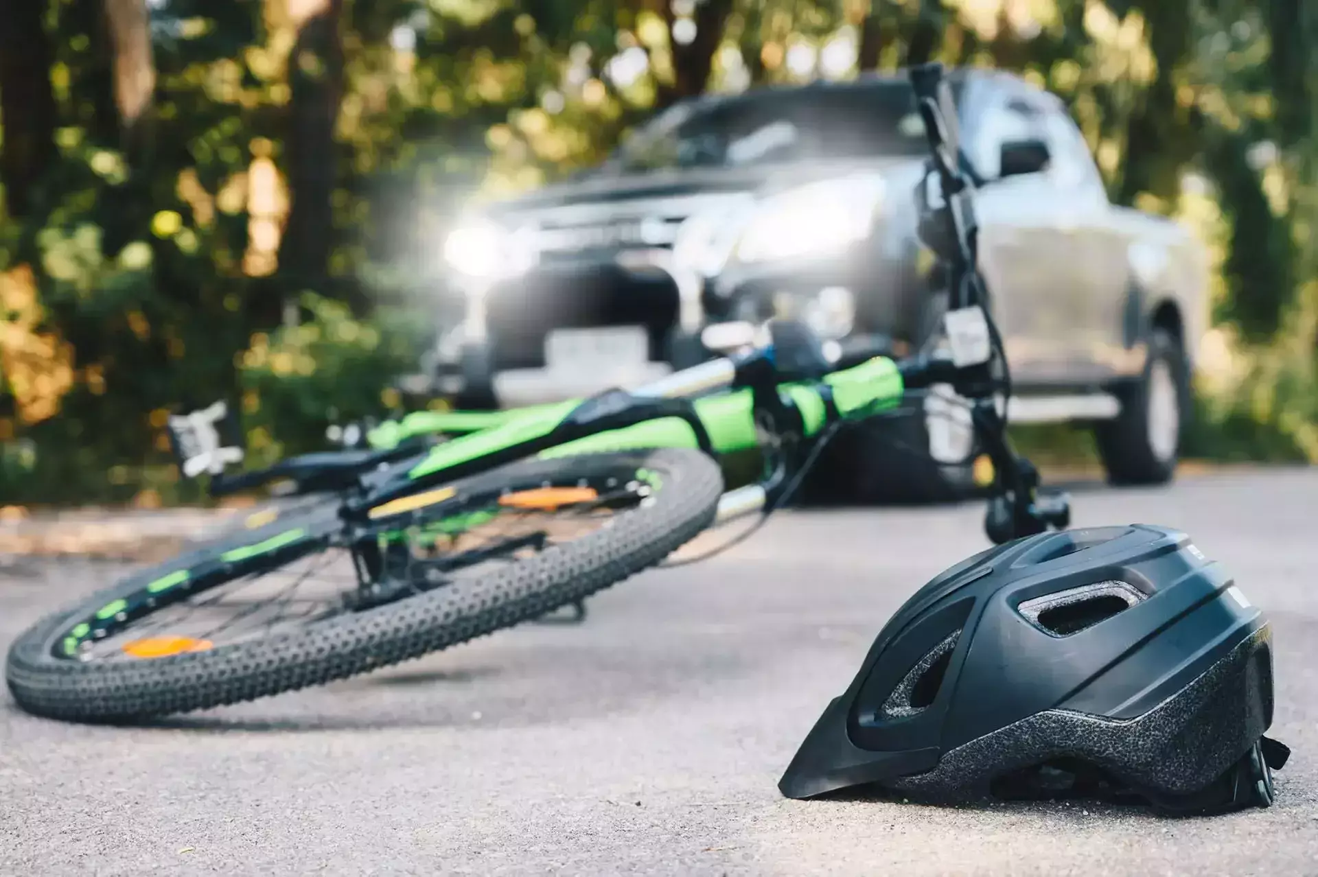 Bicicleta y casco caídos en la carretera con una camioneta detrás.