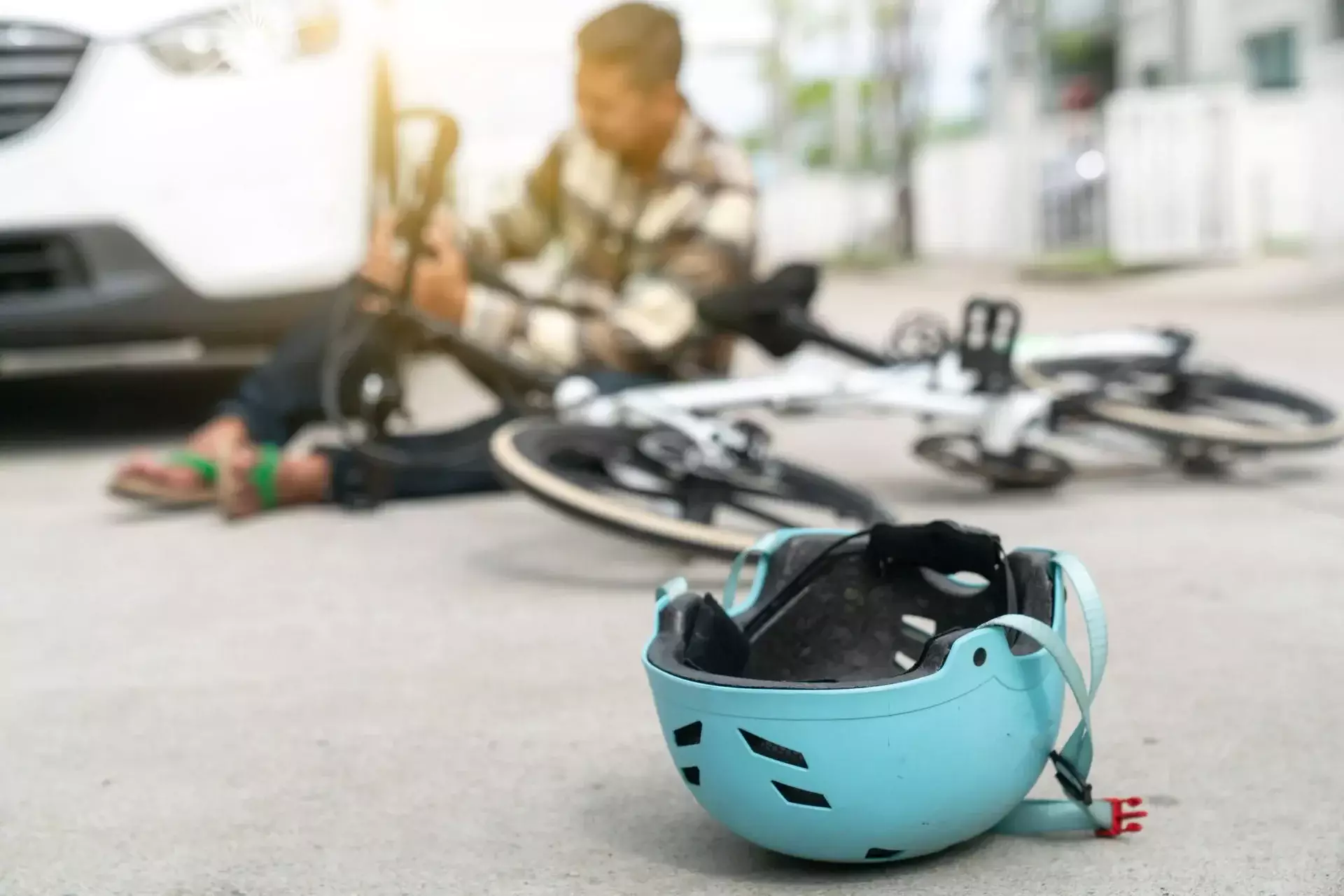 Bicycle helmet lying on the road near a fallen bicycle and vehicle after an accident