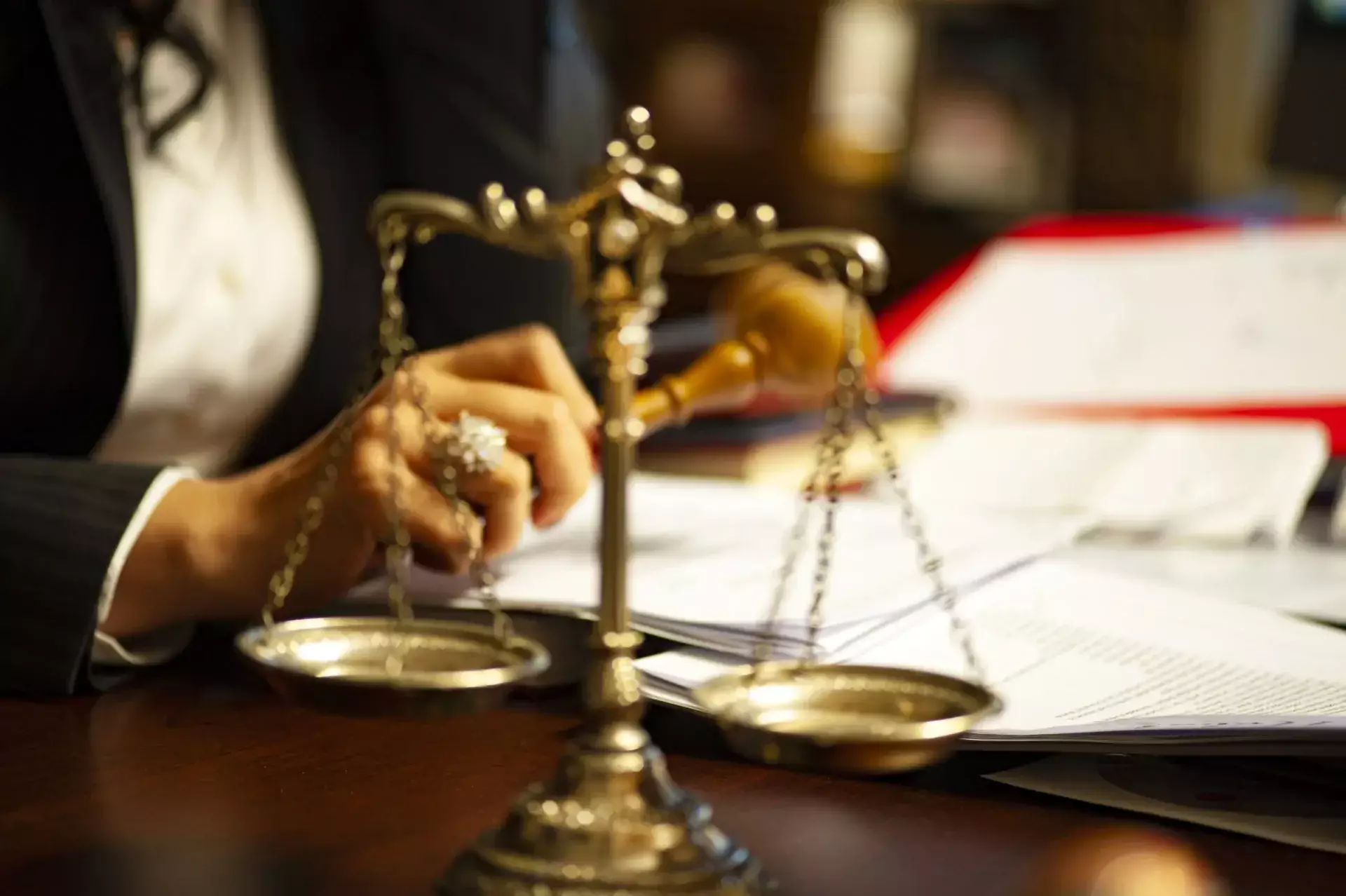 Legal professional reviewing documents with scales of justice in the foreground.