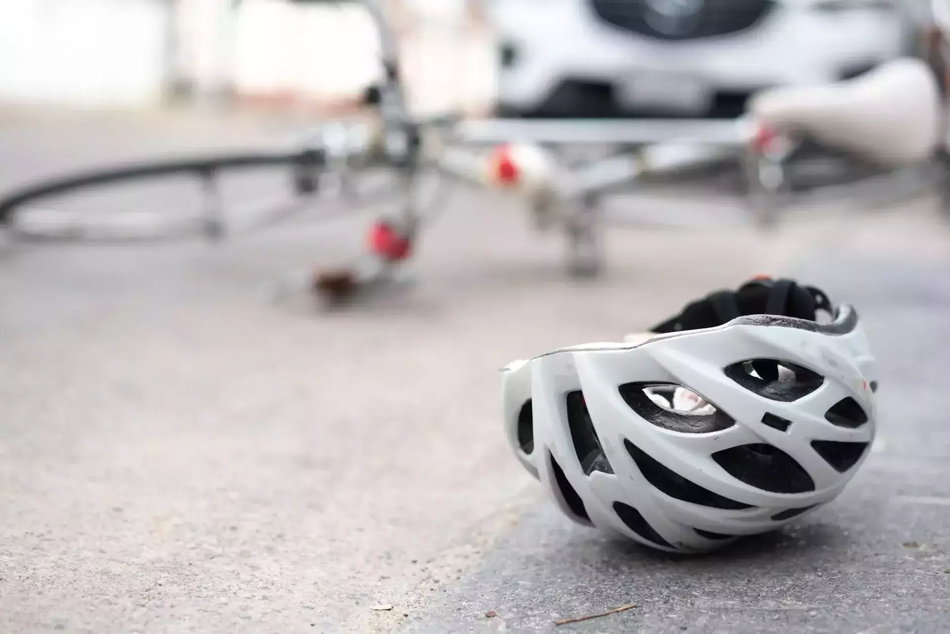 Bicycle helmet lying on the road near a fallen bicycle and vehicle after an accident
