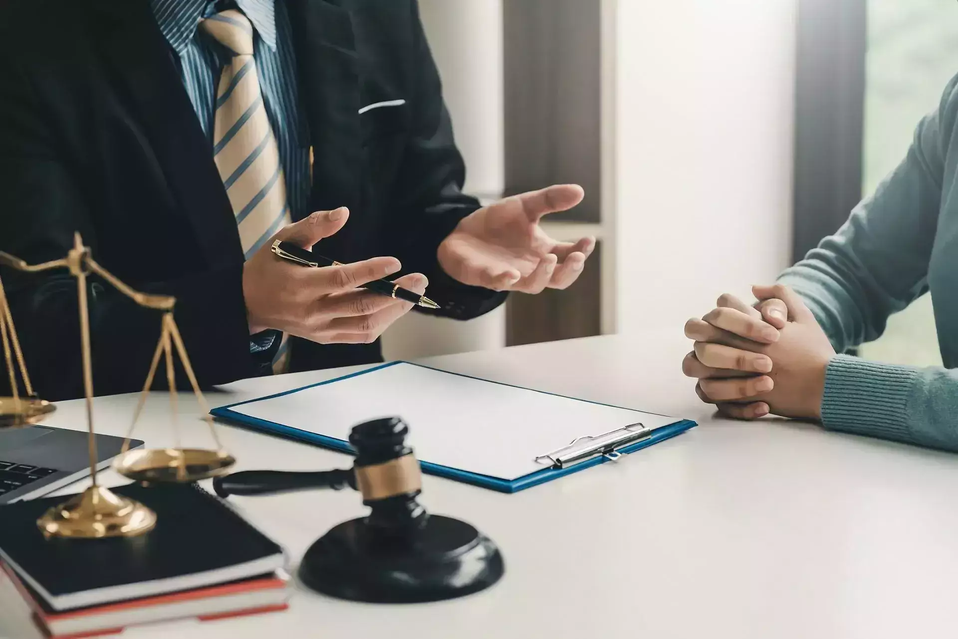 Lawyer discussing legal matters with a client at a desk with scales of justice and a gavel.