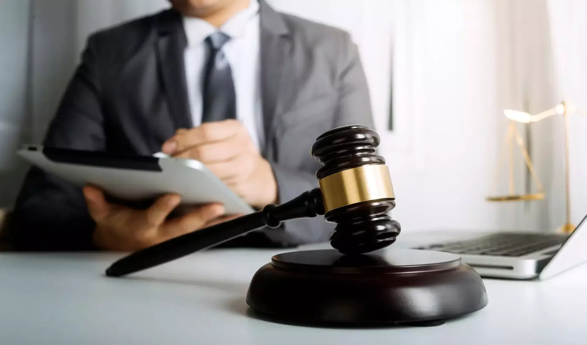 A judge's gavel on a desk with a person in the background.