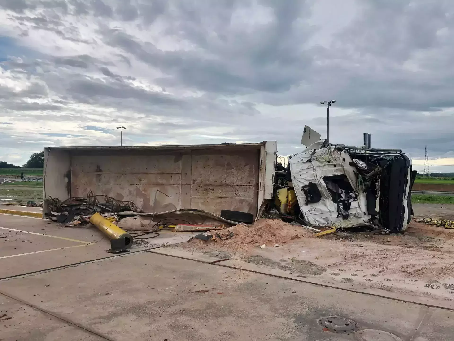 Overturned and heavily damaged white semi-truck on a roadway.