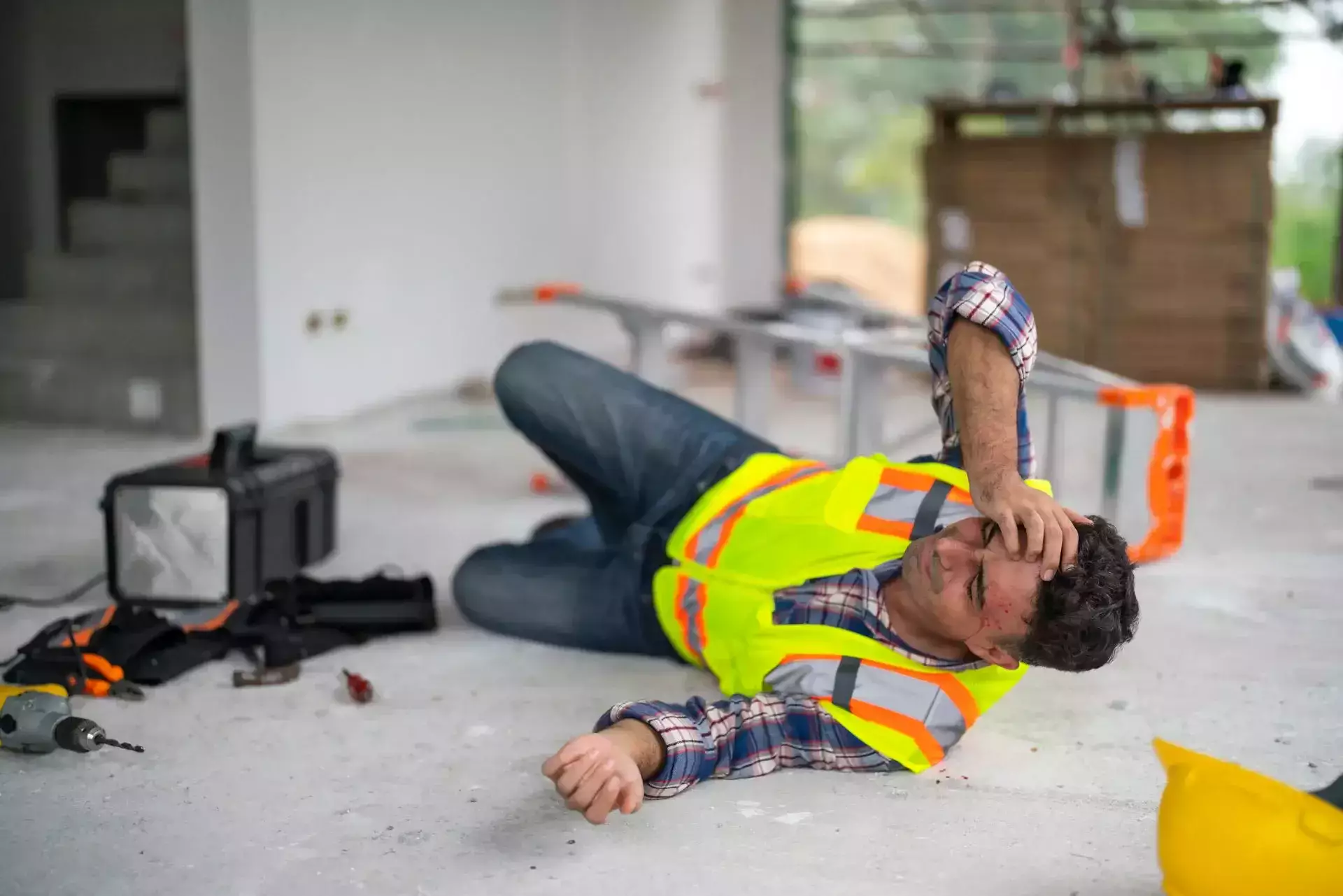 An injured construction worker lying on the ground in pain.