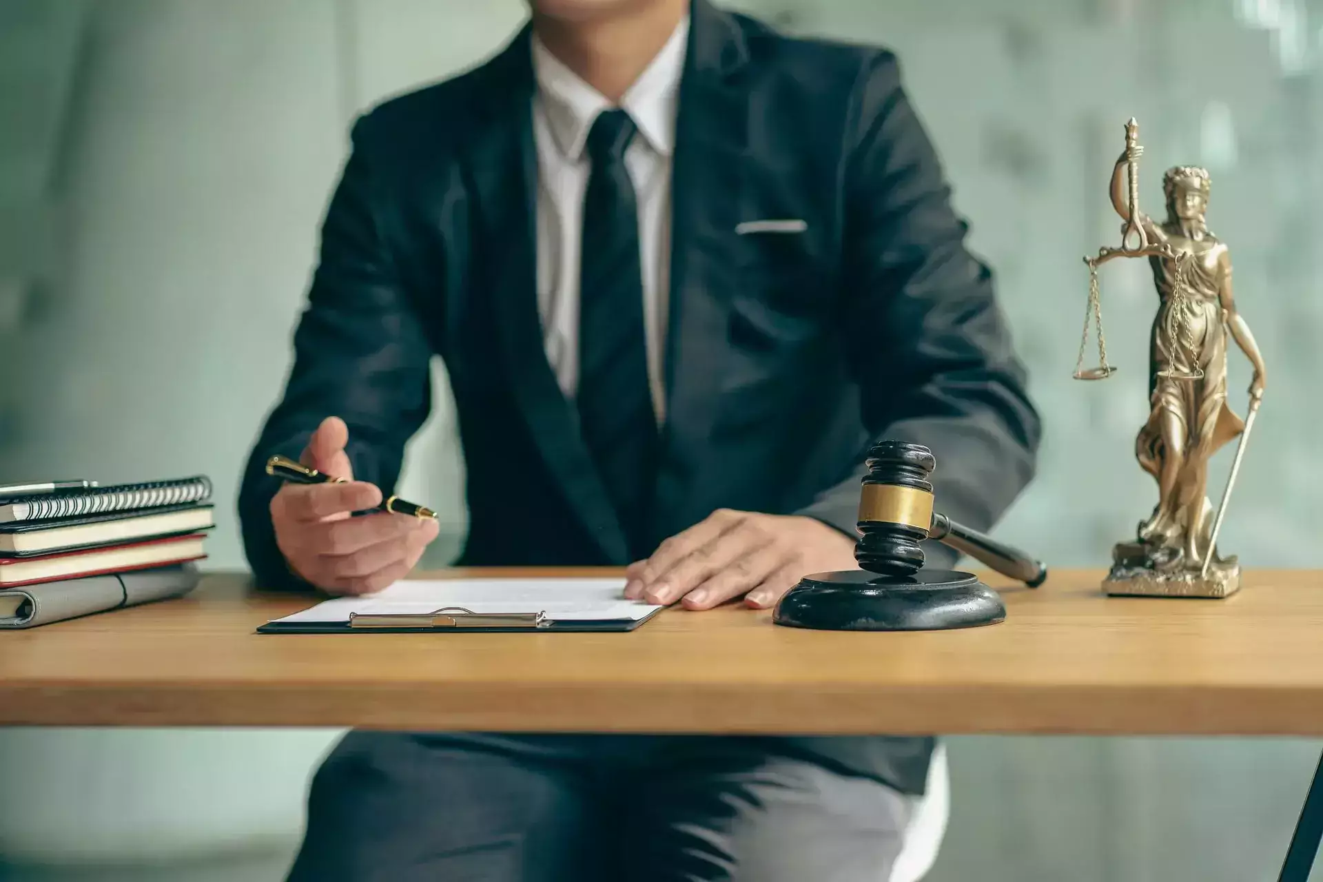 Lawyer reviewing legal documents at a desk with a gavel and Lady Justice statue