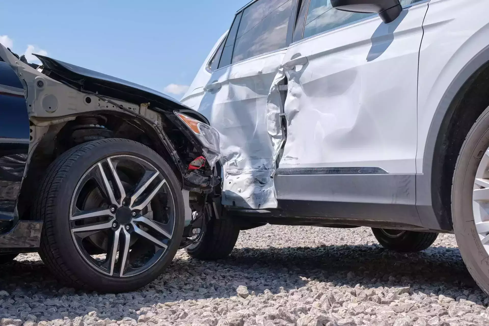 Dos autos dañados después de una colisión lateral sobre grava.