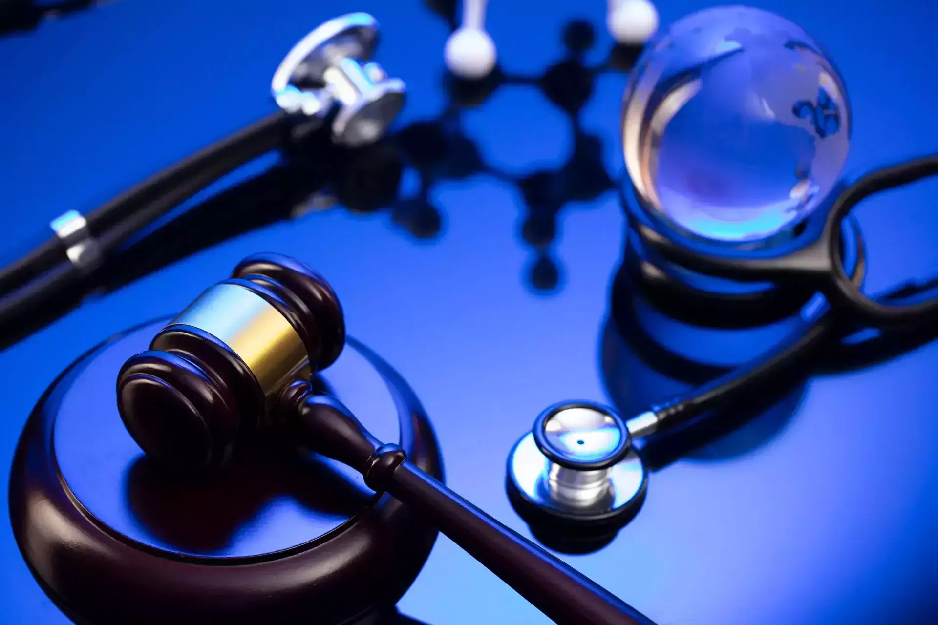 A gavel, stethoscopes, and a glass globe on a blue background.