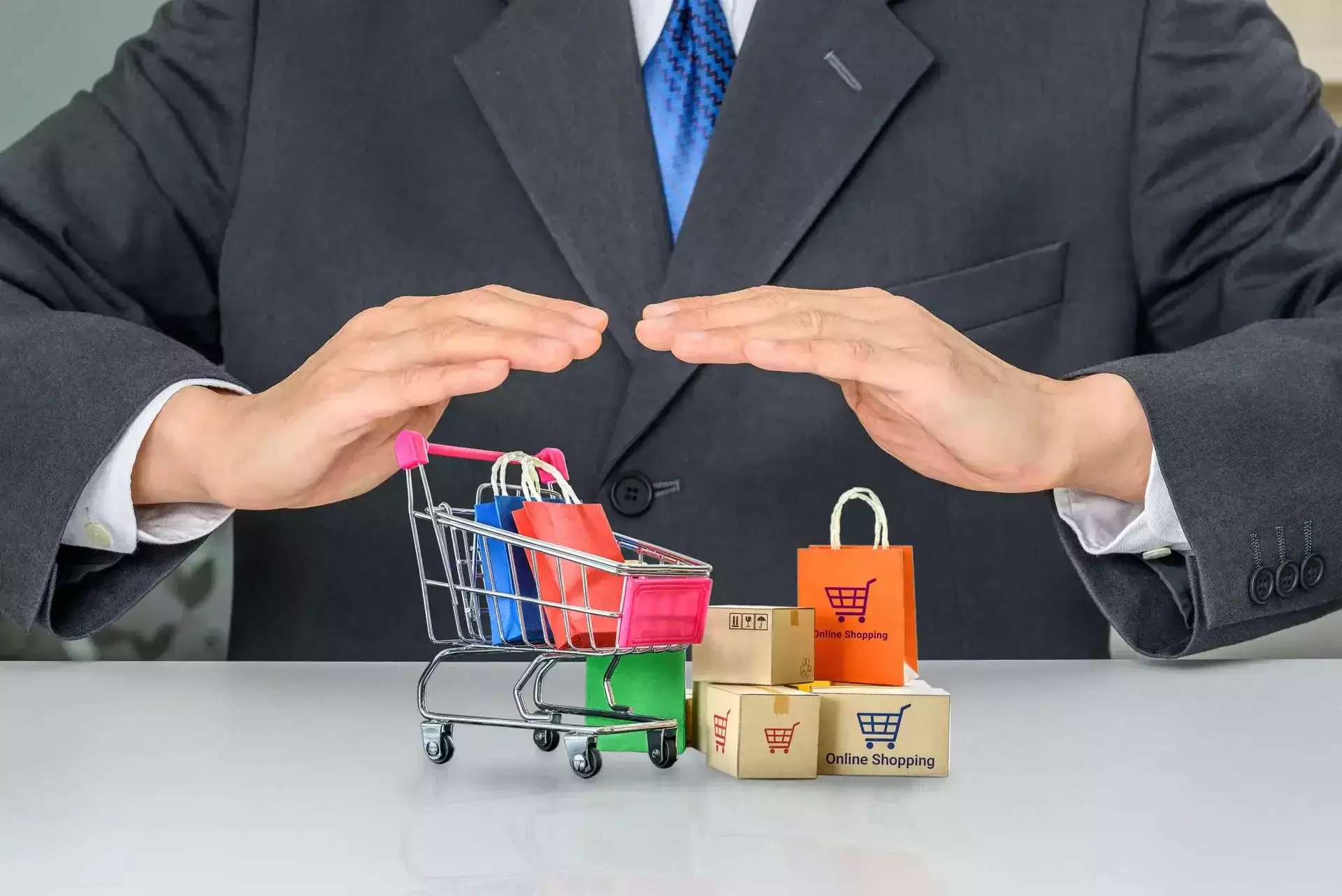A person in a suit protecting a mini shopping cart and boxes.