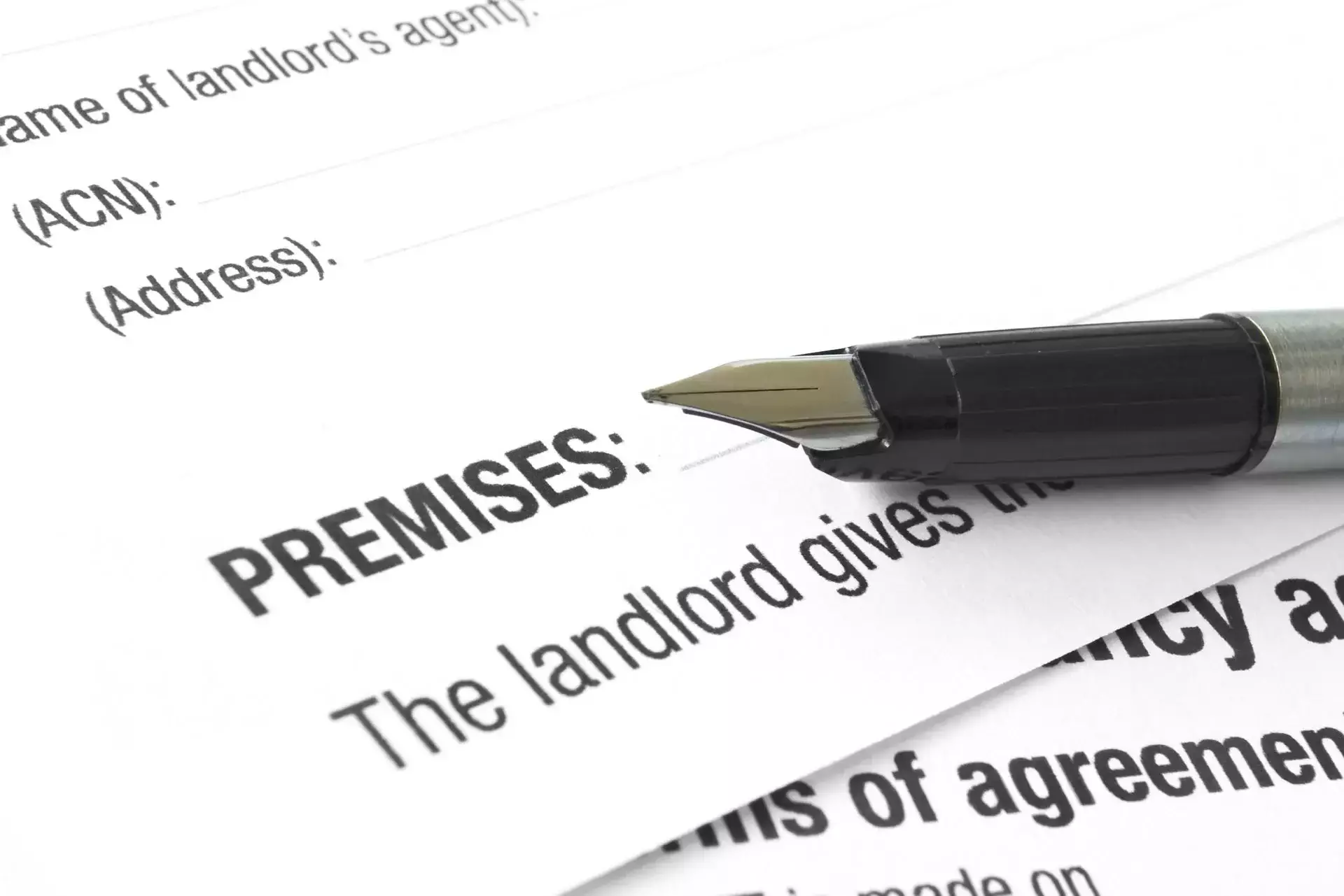 A fountain pen resting on a document with the text 'Premises:'.
